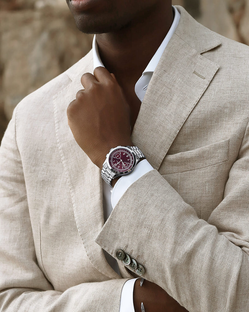 A round mens watch in rhodium-plated silver from Waldor & Co. with a burgundy colored sunray dial and a second hand. Seiko movement. The model is Chrono 39 Porto Cervo.