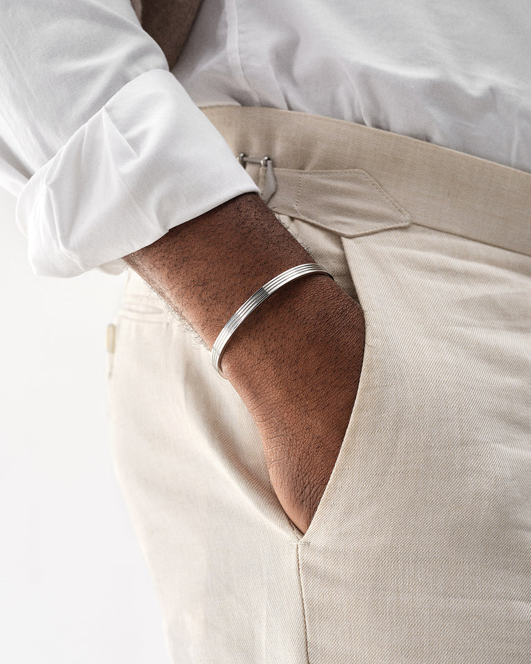 A polished stainless steel bangle in silver from Waldor & Co. One size. The model is Avant Bangle Polished