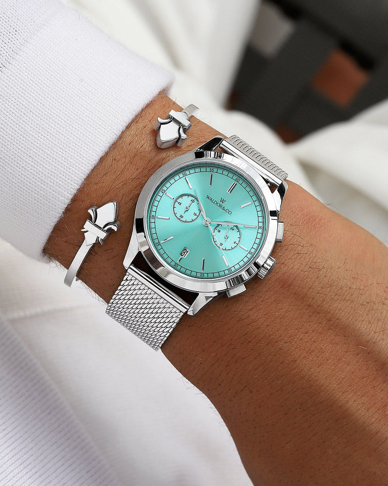 A round mens watch in rhodium-plated silver from Waldor & Co. with turquoise sunray dial and a second hand. Seiko movement. The model is Chrono 44 Sardinia 44mm.
