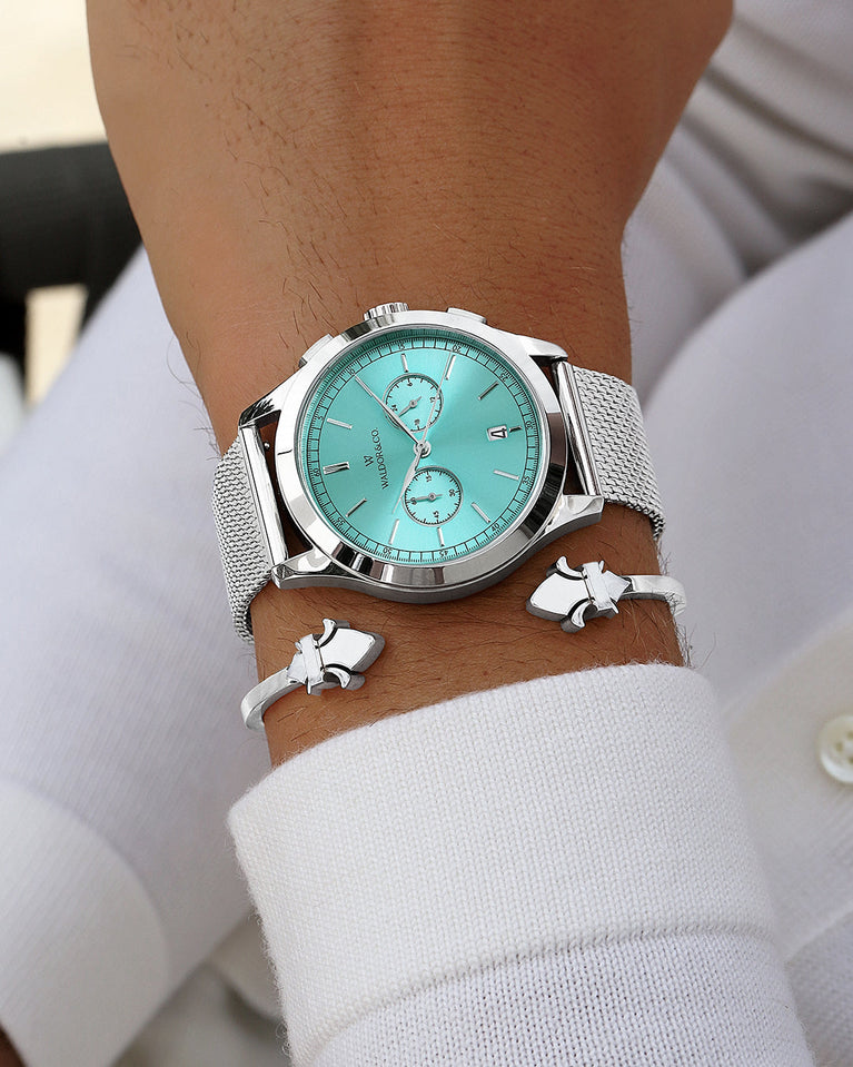 A round mens watch in rhodium-plated silver from Waldor & Co. with turquoise sunray dial and a second hand. Seiko movement. The model is Chrono 44 Sardinia 44mm.