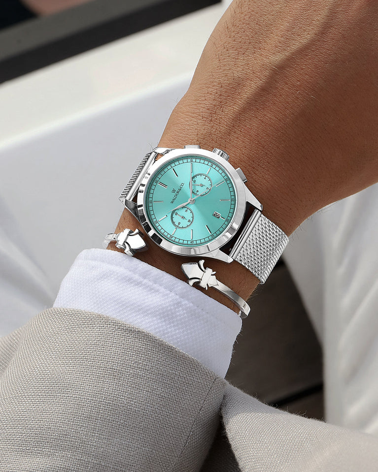 A round mens watch in rhodium-plated silver from Waldor & Co. with turquoise sunray dial and a second hand. Seiko movement. The model is Chrono 44 Sardinia 44mm.