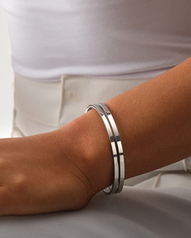 A Bangle in polished silver 316L stainless steel from Waldor & Co. One size. The model is Dual Bangle Polished.