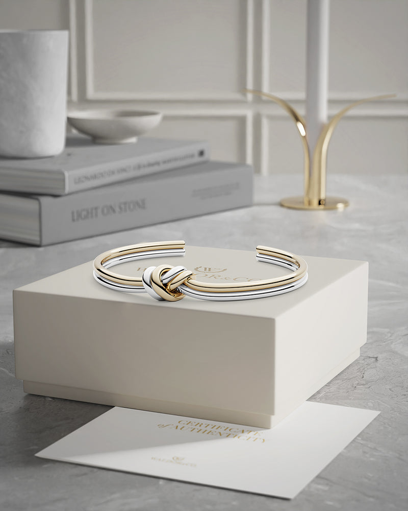 A Bangle in 14k-gold plated and silver polished 316L stainless steel from Waldor & Co. One size. The model is Dual Knot Bangle Polished.