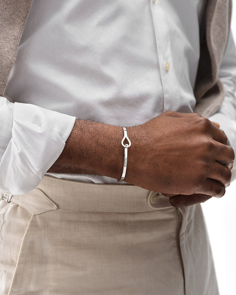A polished stainless steel bangle in silver from Waldor & Co. The model is Signature Bangle Polished