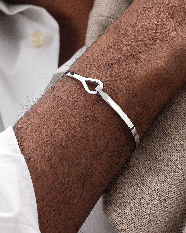 A polished stainless steel bangle in silver from Waldor & Co. The model is Signature Bangle Polished