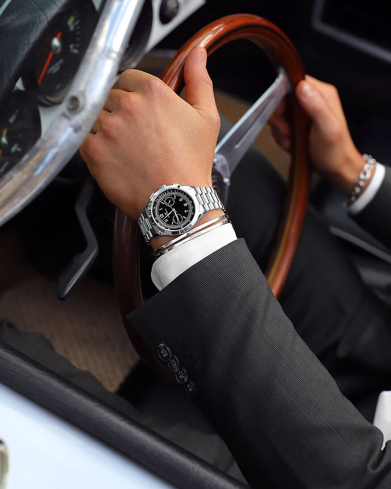 A round mens watch in rhodium-plated silver from Waldor & Co. with black sunray dial and a second hand. Seiko movement. The model is Chrono 39 Porto Cervo.