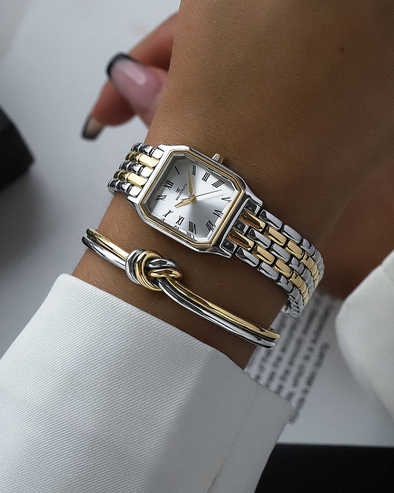 A square women’s watch and double knot bracelet in gold and silver from Waldor & co. The model is Eternal 22 Bellagio & Dual Knot Bangle.