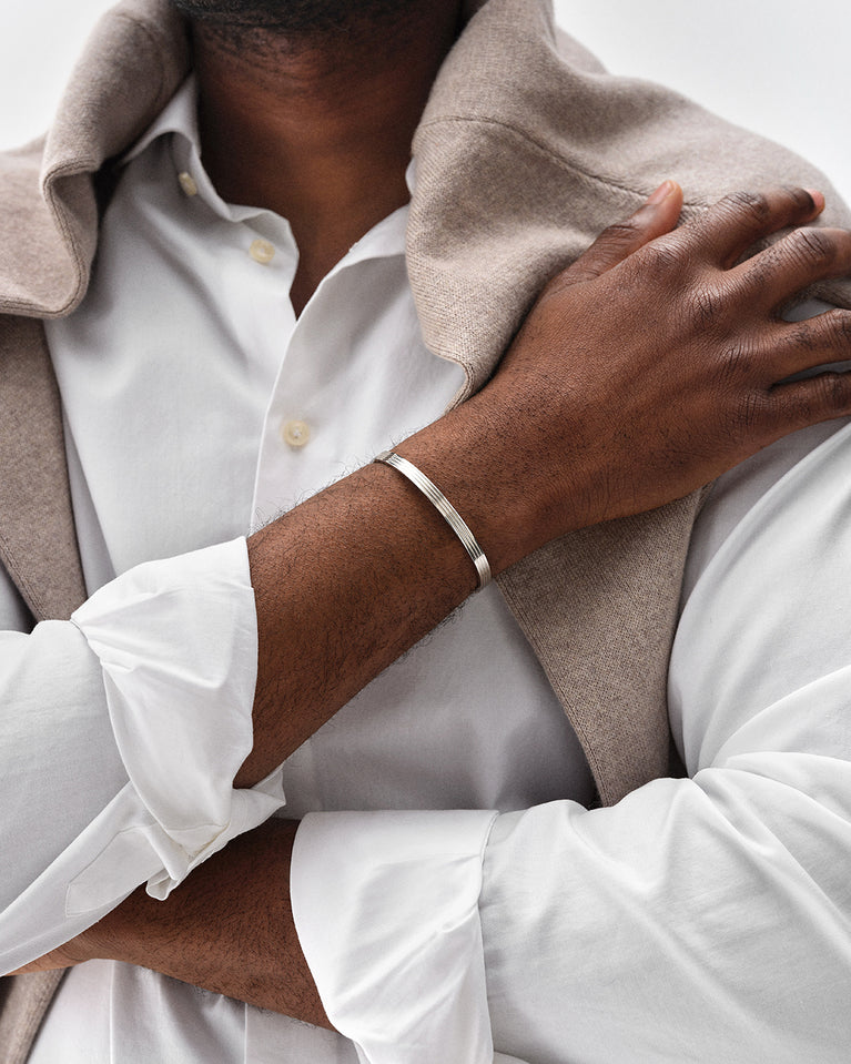 A polished stainless steel bangle in silver from Waldor & Co. One size. The model is Avant Bangle Polished