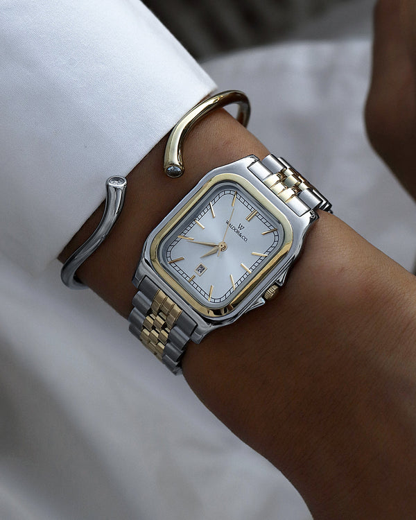  A square womens watch in silver and 14k gold from Waldor & Co. with silver sunray dial and a second hand. Seiko movement. The model is Delight 32 Chelsea 28x32mm.