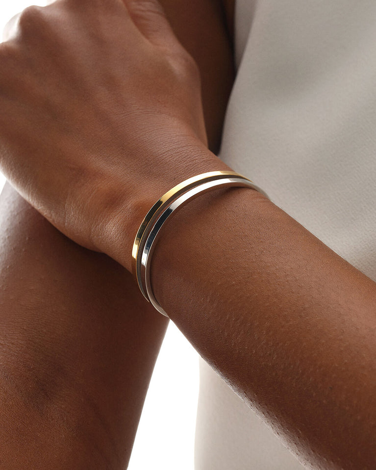 A bangle in 14k gold-plated 316L stainless steel from Waldor & Co. One size. The model is Dual Bangle Polished.