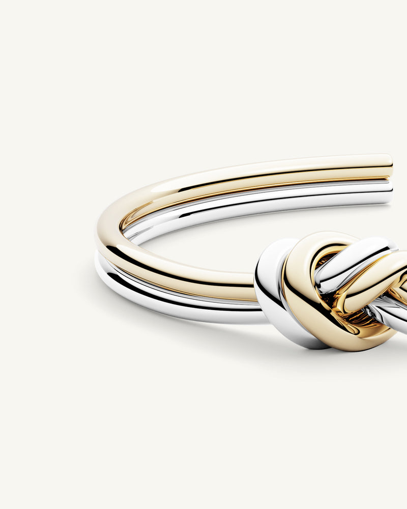 A Bangle in 14k-gold plated and silver polished 316L stainless steel from Waldor & Co. One size. The model is Dual Knot Bangle Polished.