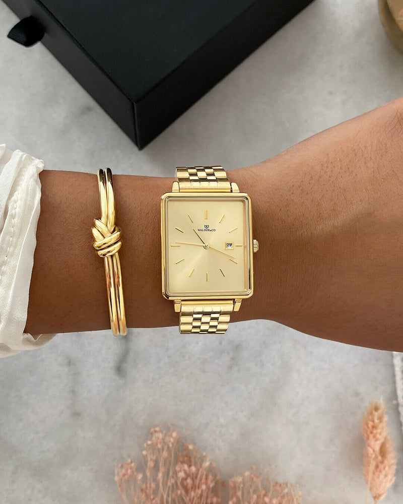 A square womens watch in 14k gold from Waldor & Co. with gold sunray dial and a second hand. Seiko movement. The model is Delight 32 Chelsea 28x32mm.